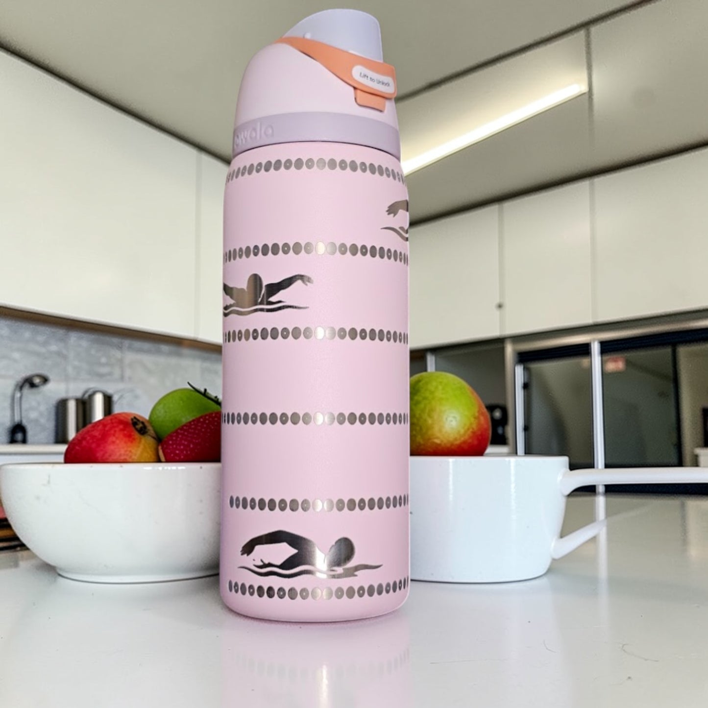 Pink water bottle with swimmer design on a kitchen counter