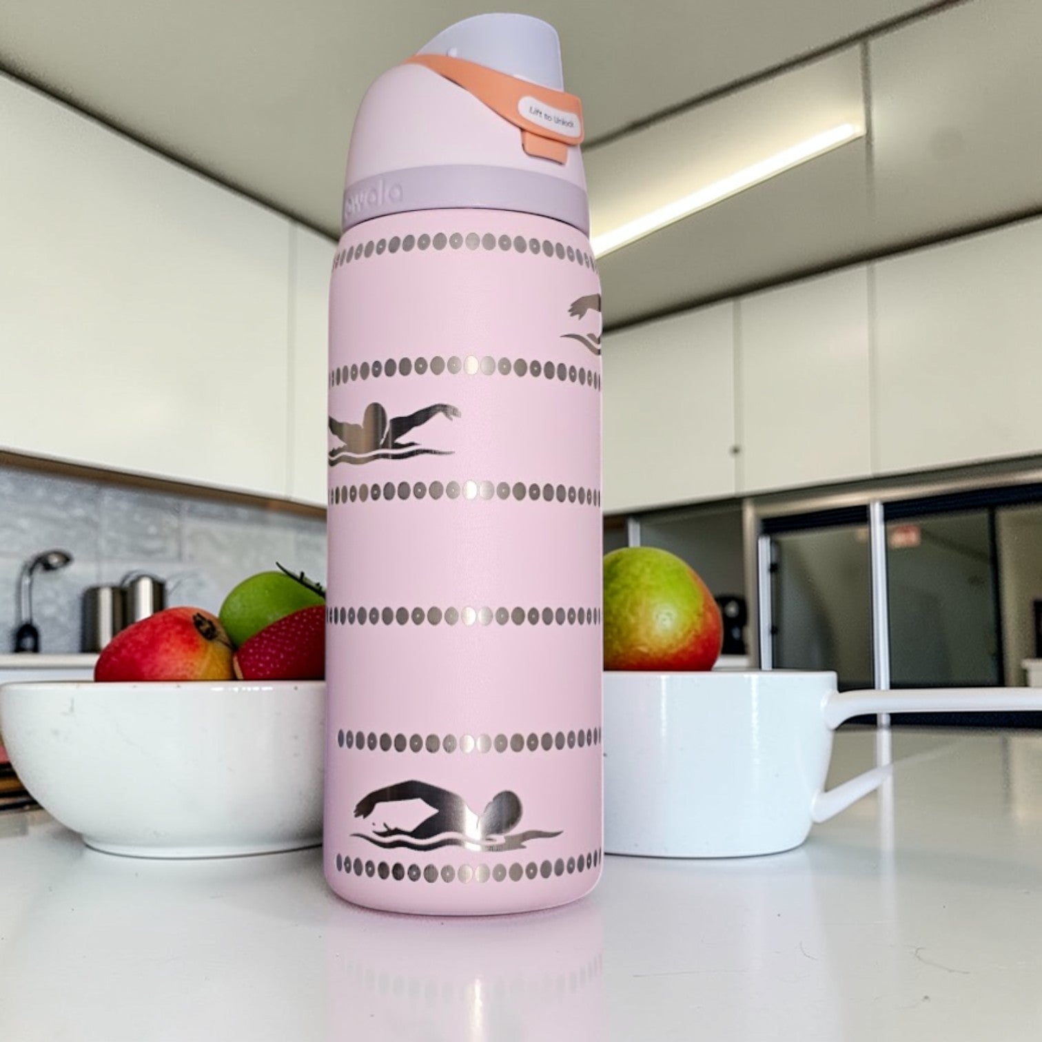 Pink water bottle with swimmer design on a kitchen counter