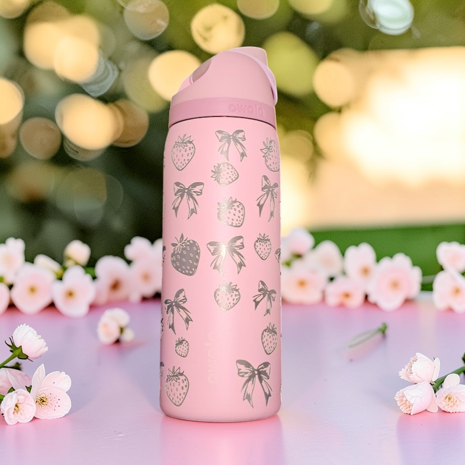 Pink thermos bottle with strawberry and bow pattern on a floral background